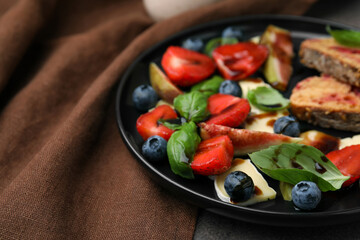 Delicious salad with brie cheese, berries and balsamic vinegar on table, closeup