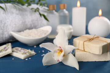 Fototapeta na wymiar Soap bars and beautiful flower on blue wooden table, closeup with space for text. Retreat concept