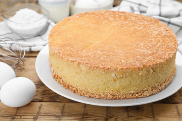 Plate with delicious sponge cake on wooden table, closeup