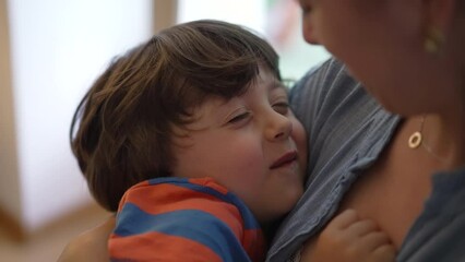 Affectionate mother holding child in arms, authentic loving tender moment between parent and little boy, motherhood concept