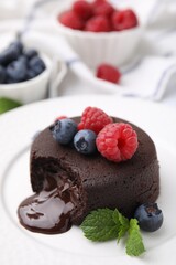 Delicious chocolate fondant, berries and mint on plate, closeup