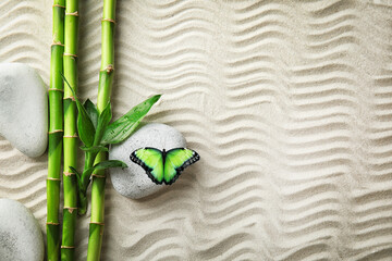 Harmony and peace. Butterfly in zen garden, bamboo branches and stones on sand with pattern, top view. Space for text