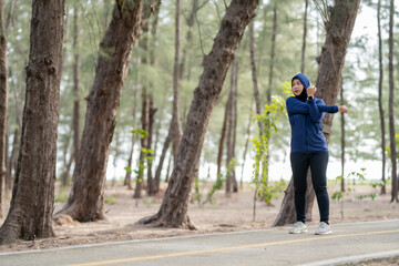 Fototapeta premium Happy cheerful Middle-aged Asian Muslim woman practicing exercise and stretching and enjoy jogging at the park close up with copy space. Modern muslim woman lifestyles and diversity concept.