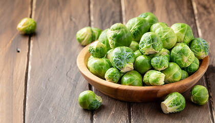 Green raw Brussels sprouts in a wooden bowl on a rustic wooden table, selective focus
