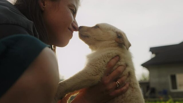 Positive woman with glad expression and her puppy being satisfied, having good relationships, cuddling outdoors. Domestic animals and people.