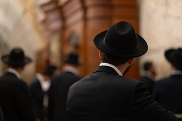 Jewish men in traditional Haredi clothes pray alongside a Torah ark at the Kotel, known as the...