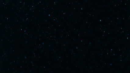 Glowing particles. Sparkles texture. Shimmer rain. Blur blue color light dust flakes floating on dark black free space abstract background.