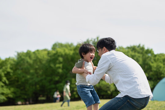 公園で子供と一緒に遊ぶ父親