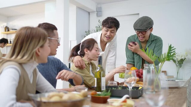 Group of Cheerful Asian man and woman eating food and drinking wine celebration dinner party together at home. Happy people friends enjoy and fun celebrating reunion meeting holiday event vacation.