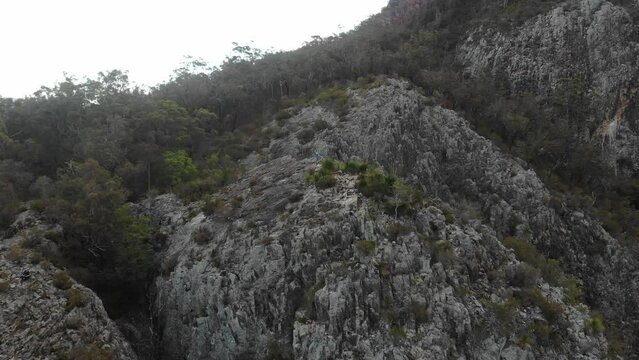 aerial view of brave hiker girl standing on a razorback ridge at the top of mount greville admiring the panorama of lake maroon; moogerah peaks national park near brisbane, queensland, australia