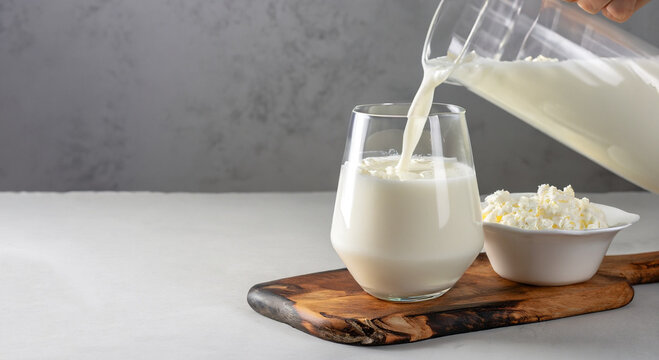 Kefir or Ayran fermented drink is poured into a glass from a jug, as well as cottage cheese in a bowl on a light gray background, Copy space, Close up