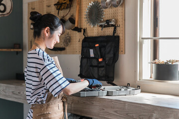 家のガレージで工具を使う女性（DIY・クラフト・日曜大工・ワークショップ・体験教室・リフォーム）
 - obrazy, fototapety, plakaty