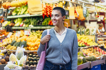 hispanic young woman with skinhead or short hair shopping vegetables on traditional market or grocery 