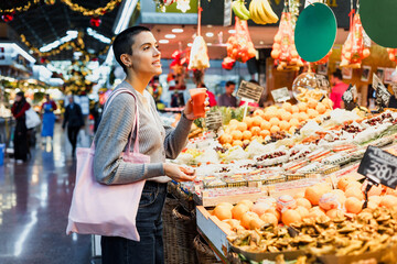 hispanic young woman with skinhead or short hair shopping vegetables on traditional market or grocery 