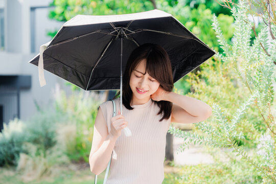 日傘を差して外を歩く若い女性