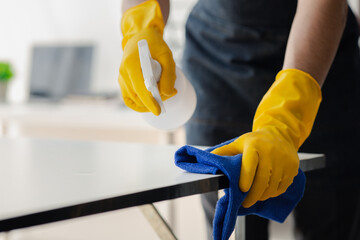 Person cleaning the room, cleaning staff is using cloth and spraying disinfectant to wipe the...