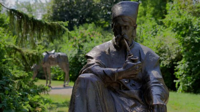 Memorial to Ukrainian Cossacks (Kosaken Denkmal) in T&uuml;rkenschanzpark in Vienna during a sunny day surrounded by trees. Sculpture of a man smoking a pipe with his horse in the background.