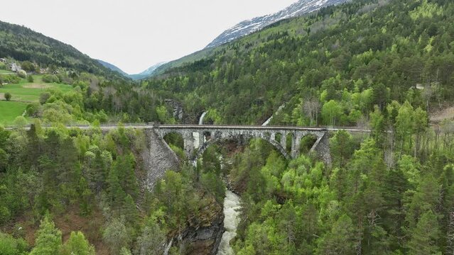 Aerial approaching historic Kylling railway bridge passing above Verma river in Rauma Norway