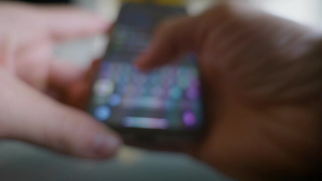 Blurry close-up view of caucasian hands using smartphone to send text message