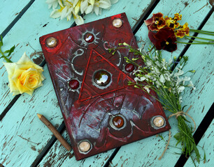 Still life with beautiful magic book of spells and flowers against wooden background. Occult,...