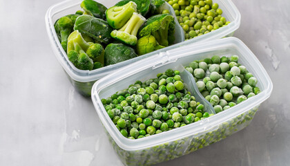 Frozen vegetables such as green peas, green beans and broccoli in the storage boxes on the light gray background. Close-up