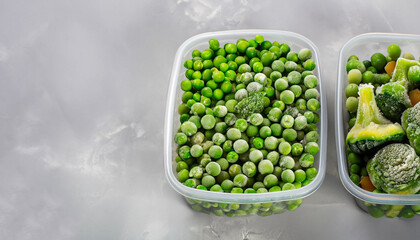 Frozen vegetables such as green peas, green beans and broccoli in the storage boxes on the light gray background. Close-up