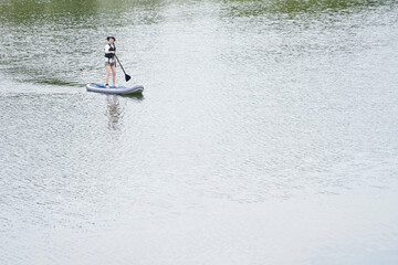 Naklejka premium 休日の川でサップを楽しむ日本人の女性