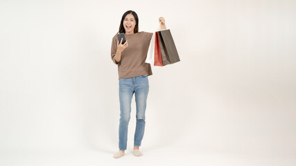 A beautiful Asian woman is carrying her shopping bags and her smartphone. Online shopping