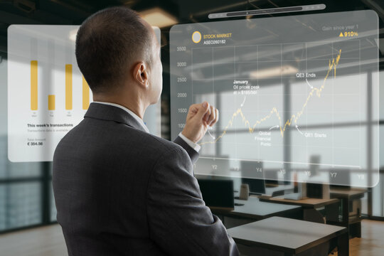 Asian businessman in the office interacting to augmented reality or virtual touch screen reviewing graph for business data analysis