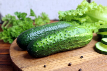 Fresh juicy cucumbers lie on a wooden cutting board.