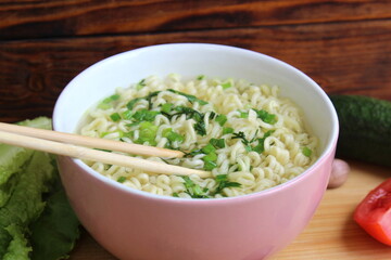 The bowl contains noodles with wooden sticks.	