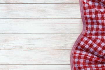 A cotton checkered napkin lies on a wooden background.