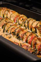 Zucchini casserole with tomatoes, cheese and spices and herbs in a black casserole dish