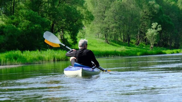 Family kayak trip for seigneur and senora. An elderly married couple rowing a boat on the river, a water hike, a summer adventure. Age-related sports, mental youth and health, tourism, active old age