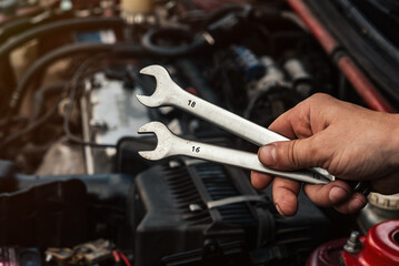 wrenches in the wizard's hand close-up against the background of the car being repaired