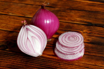 Purple chopped and whole onions lie on a wooden table.