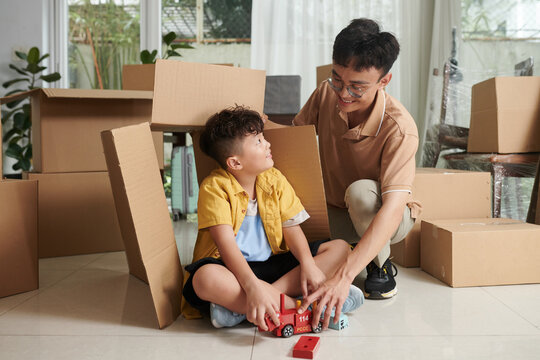 Father and son playing when unpacking boxes in new home