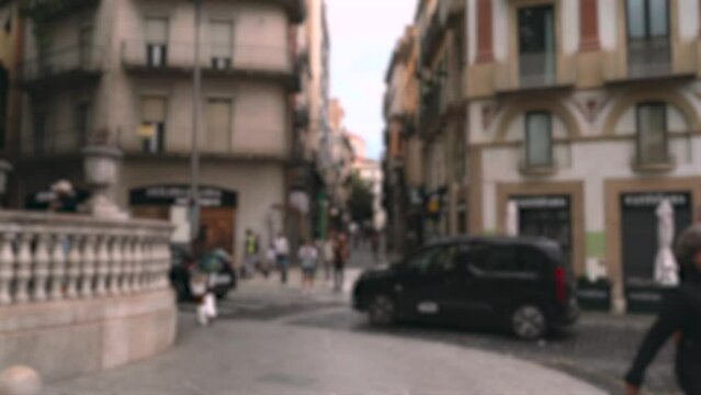 Background, blurry video. View of the pedestrian street in the city center, along which people walk, and the roadway with cars.