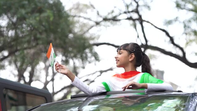 indian little girl exit from car sunroof and waving national flag.