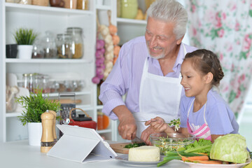 Senior man with granddaughter preparing dinner