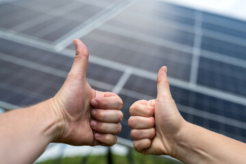 Electric power engineer thumbs up against solar panels after finish installation