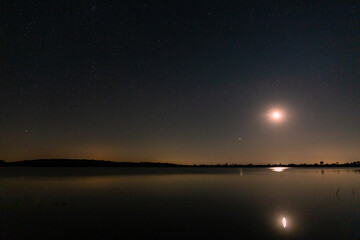 Tabuyo del Monte reservoir at night with stars and the moon before sunrise, Leon, Spain.