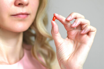 Close-up of a Coenzyme Q10 capsule in a woman's hand.