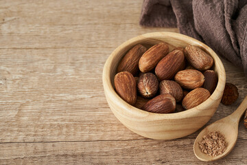 nutmeg whole muscat nut in wood bowl on wooden table background. nutmeg whole muscat nut. pile of nutmeg whole muscat nut food background                                           