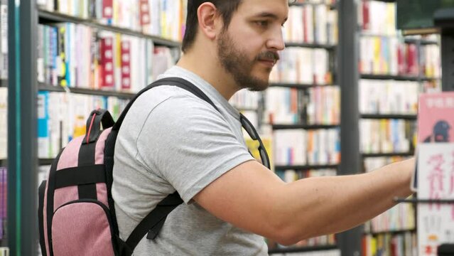 Latin tourist putting a comic on the self at a Japanese comic book store in Tokyo.
