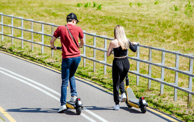 Girl and guy rides an electric scooter in the summer Park
