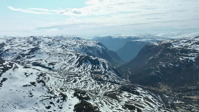 Sognefjellet mountain pass descent to Luster and Tindevegen mountain pass road leading to Aardal seen winding up hills in left frame - Aerial