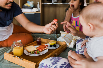 latin family having breakfast on bed at home in Mexico, hispanic mother, father, daughter and son at morning in Latin America