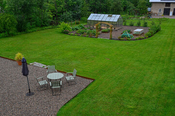 Looking out over back garden with seating area and green house