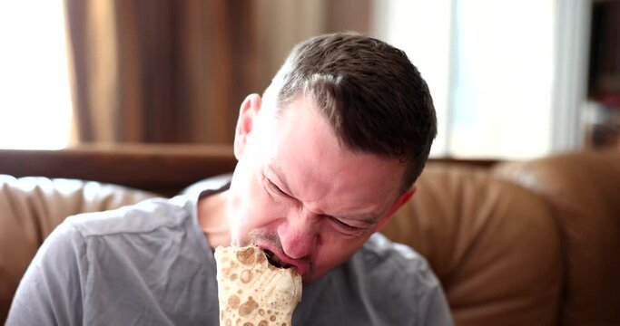 Hungry young man eats delicious shawarma with pleasure. Delicious snacks and junk food concept